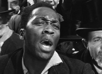 Movie still from “Miracle in Milan” (1951), directed by Vittorio De Sica – A black and white photo of a man with his mouth wide open; Close Up shot, High angle