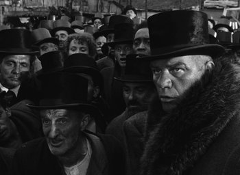 Movie still from “Miracle in Milan” (1951), directed by Vittorio De Sica – A group of men wearing top hats and coats; Medium shot, Low angle