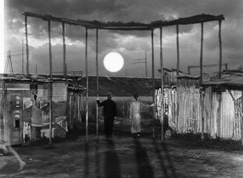 Movie still from “Miracle in Milan” (1951), directed by Vittorio De Sica – Two men are standing in an enclosed area; Wide shot, Low angle