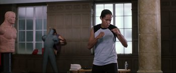Movie still from “Miss Congeniality 2: Armed & Fabulous” (2005), directed by John Pasquin – A man in a black and white t - shirt is boxing in a room; Medium shot, Low angle