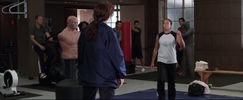 Movie still from “Miss Congeniality 2: Armed & Fabulous” (2005), directed by John Pasquin – A group of people standing in a room; Medium shot, Over the shoulder angle