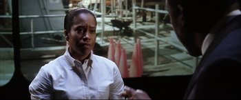 Movie still from “Miss Congeniality 2: Armed & Fabulous” (2005), directed by John Pasquin – A woman in front of a picture of a construction site; Close Up shot, Over the shoulder angle