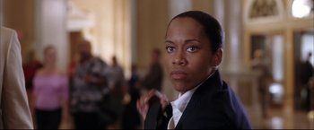 Movie still from “Miss Congeniality 2: Armed & Fabulous” (2005), directed by John Pasquin – A woman wearing a suit and tie in front of a group of people; Close Up shot, Low angle