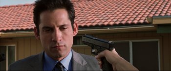 Movie still from “Miss Congeniality 2: Armed & Fabulous” (2005), directed by John Pasquin – A man in a suit and tie holding a gun; Close Up shot, Over the shoulder angle