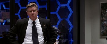 Movie still from “Miss Congeniality 2: Armed & Fabulous” (2005), directed by John Pasquin – A man wearing a suit and tie standing in front of a mirror; Medium shot, Over the shoulder angle