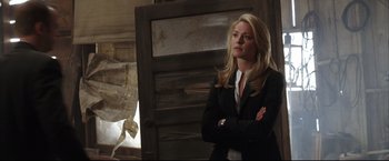 Movie still from “Miss Congeniality 2: Armed & Fabulous” (2005), directed by John Pasquin – A woman standing in front of a wooden door wearing a black jacket; Medium shot, Over the shoulder angle