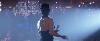 Movie still from “Miss Congeniality 2: Armed & Fabulous” (2005), directed by John Pasquin – A woman wearing a hat is holding a remote control; Medium shot, Over the shoulder angle