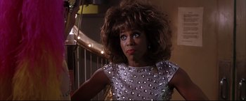 Movie still from “Miss Congeniality 2: Armed & Fabulous” (2005), directed by John Pasquin – A woman in a silver sequined dress with a big curly brown hair; Close Up shot, Over the shoulder angle