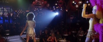 Movie still from “Miss Congeniality 2: Armed & Fabulous” (2005), directed by John Pasquin – A crowd of people sitting at tables in front of a stage; Wide shot, Over the shoulder angle