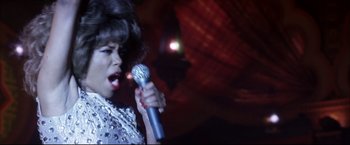 Movie still from “Miss Congeniality 2: Armed & Fabulous” (2005), directed by John Pasquin – A woman is singing into a microphone in front of an audience; Close Up shot, Low angle