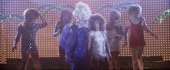 Movie still from “Miss Congeniality 2: Armed & Fabulous” (2005), directed by John Pasquin – A group of people in costumes in front of a neon sign; Wide shot, Low angle