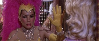 Movie still from “Miss Congeniality 2: Armed & Fabulous” (2005), directed by John Pasquin – A woman in a yellow outfit and pink wig; Close Up shot, Over the shoulder angle