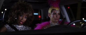 Movie still from “Miss Congeniality 2: Armed & Fabulous” (2005), directed by John Pasquin – Two drag queens sitting in the back seat of a car; Close Up shot, Over the shoulder angle