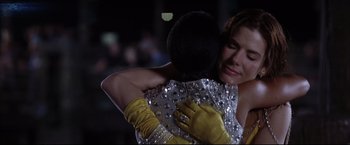 Movie still from “Miss Congeniality 2: Armed & Fabulous” (2005), directed by John Pasquin – A woman in a silver dress is hugging another woman in a yellow dress; Close Up shot, Low angle