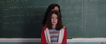 Movie still from “Miss Congeniality 2: Armed & Fabulous” (2005), directed by John Pasquin – A young girl in front of a chalkboard; Medium shot, Over the shoulder angle