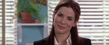 Movie still from “Miss Congeniality 2: Armed & Fabulous” (2005), directed by John Pasquin – A person wearing a suit and smiling; Close Up shot, Over the shoulder angle