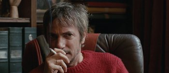 Movie still from “Mister Lonely” (2007), directed by Harmony Korine – A man smoking a cigarette while sitting on a couch; Close Up shot, Low angle