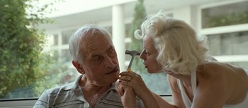 Movie still from “Mister Lonely” (2007), directed by Harmony Korine – An older man and a younger woman holding a hammer; Close Up shot, Over the shoulder angle