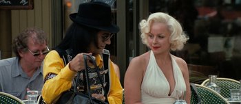 Movie still from “Mister Lonely” (2007), directed by Harmony Korine – A woman in a white dress holding a purse next to another woman in a white dress; Medium shot, Over the shoulder angle