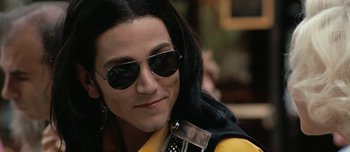 Movie still from “Mister Lonely” (2007), directed by Harmony Korine – A man with long black hair wearing sunglasses; Close Up shot, Over the shoulder angle