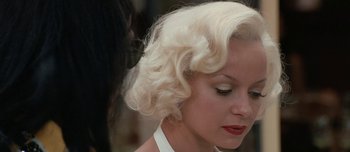 Movie still from “Mister Lonely” (2007), directed by Harmony Korine – A woman with blonde hair and red lipstick looking to her left; Close Up shot, Over the shoulder angle