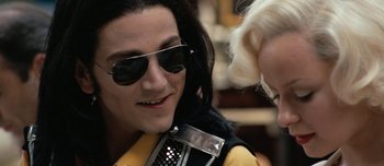 Movie still from “Mister Lonely” (2007), directed by Harmony Korine – A man wearing sunglasses talking to a woman; Close Up shot, Over the shoulder angle