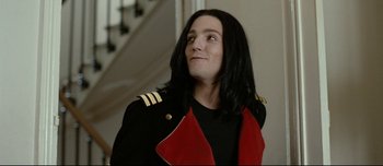 Movie still from “Mister Lonely” (2007), directed by Harmony Korine – A man with long black hair wearing a black jacket; Close Up shot, Low angle