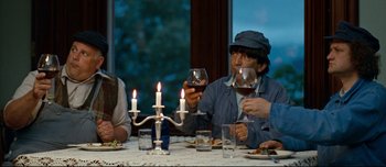 Movie still from “Mister Lonely” (2007), directed by Harmony Korine – A group of people sitting around a table with wine glasses; Medium shot, Low angle