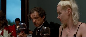 Movie still from “Mister Lonely” (2007), directed by Harmony Korine – A man and a woman sitting next to each other holding glasses of wine; Close Up shot, Over the shoulder angle