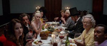 Movie still from “Mister Lonely” (2007), directed by Harmony Korine – A group of people sitting at a table drinking wine; Medium shot, High angle