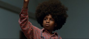 Movie still from “Mister Lonely” (2007), directed by Harmony Korine – A young boy with an afro raises his hand; Close Up shot, Low angle