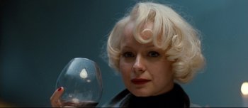 Movie still from “Mister Lonely” (2007), directed by Harmony Korine – A woman with blonde hair holding a wine glass; Close Up shot, Over the shoulder angle