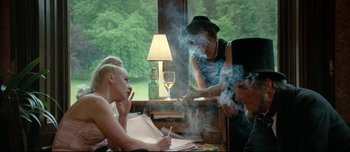 Movie still from “Mister Lonely” (2007), directed by Harmony Korine – A woman sitting in front of a man smoking a cigarette; Medium shot, Over the shoulder angle