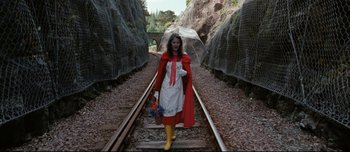Movie still from “Mister Lonely” (2007), directed by Harmony Korine – A woman dressed as little red riding hood walking down a train track; Wide shot, High angle