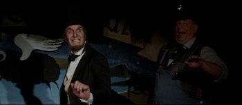 Movie still from “Mister Lonely” (2007), directed by Harmony Korine – A man in a suit and top hat is smiling; Medium shot, Low angle
