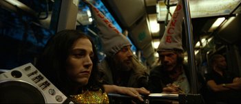 Movie still from “Mister Lonely” (2007), directed by Harmony Korine – A woman sitting next to two men on a bus; Medium shot, High angle