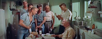 Movie still from “Mister Roberts” (1955), directed by John Ford – A group of men standing around a table; Medium shot, High angle