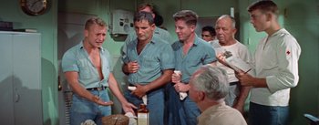 Movie still from “Mister Roberts” (1955), directed by John Ford – A group of men standing next to each other in a room; Medium shot, High angle