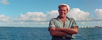 Movie still from “Mister Roberts” (1955), directed by John Ford – A man with his arms crossed in front of a body of water; Medium shot, Low angle