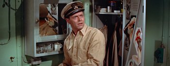 Movie still from “Mister Roberts” (1955), directed by John Ford – A man wearing a hat in a room; Medium shot, Low angle