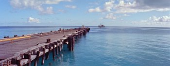 Movie still from “Mister Roberts” (1955), directed by John Ford – A pier that has some people on it in the water; Extreme Wide shot, High angle