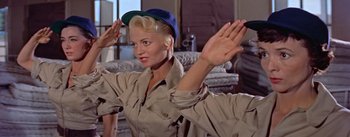 Movie still from “Mister Roberts” (1955), directed by John Ford – A woman with a hat on her head and hands up; Medium shot, Low angle