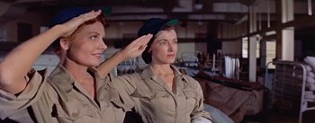 Movie still from “Mister Roberts” (1955), directed by John Ford – Two women saluting while wearing hats in a room; Medium shot, Low angle