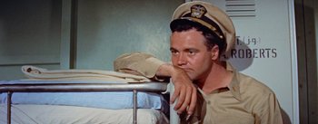 Movie still from “Mister Roberts” (1955), directed by John Ford – A man in a uniform leaning on a bed; Medium shot, High angle