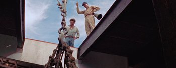 Movie still from “Mister Roberts” (1955), directed by John Ford – Two men standing next to each other on the roof of a building; Medium shot, Low angle
