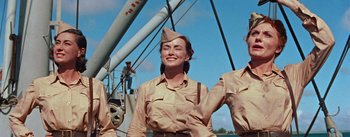 Movie still from “Mister Roberts” (1955), directed by John Ford – A woman in a military uniform standing next to a boat; Medium shot, Low angle