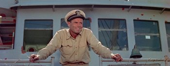 Movie still from “Mister Roberts” (1955), directed by John Ford – A man wearing a hat sitting on top of a boat; Medium shot, Low angle