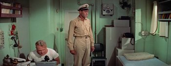 Movie still from “Mister Roberts” (1955), directed by John Ford – A man in a uniform standing in a room; Medium shot, High angle