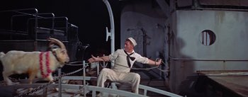 Movie still from “Mister Roberts” (1955), directed by John Ford – A man sitting on top of a boat holding a rope; Medium shot, High angle