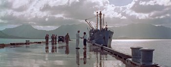 Movie still from “Mister Roberts” (1955), directed by John Ford – Two people standing on a dock near a boat; Extreme Wide shot, Low angle